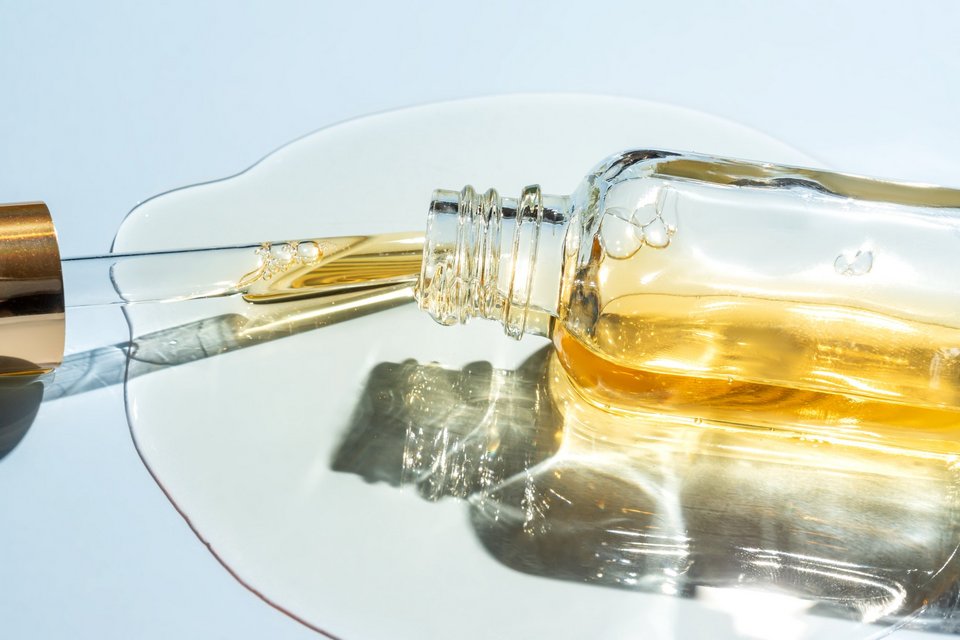 Cosmetic pipette with oil on blue background close-up. Stylish concept of organic essences, beauty and health products. Modern apothecary. Close up