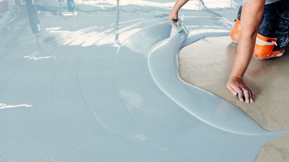 Construction worker smoothing and leveling concrete screed on the floor