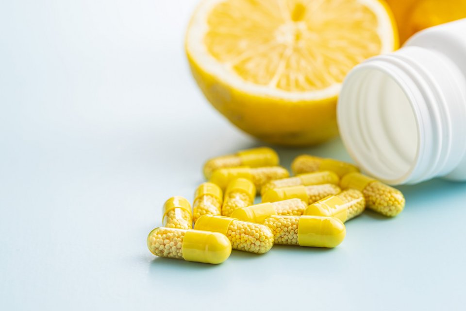 Vitamin capsules. Vitamin C pills, lemon fruit and pill bottle.
